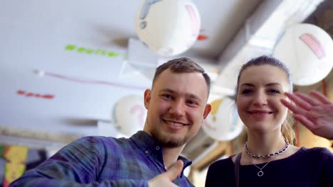 Happy-woman-and-man-smiles-to-camera-and-waves-hands