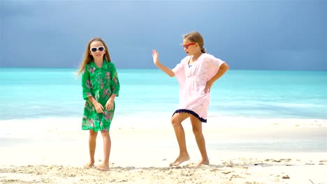 Entzückende-kleine-Mädchen-eine-Menge-Spaß-am-tropischen-Strand-spielen-zusammen