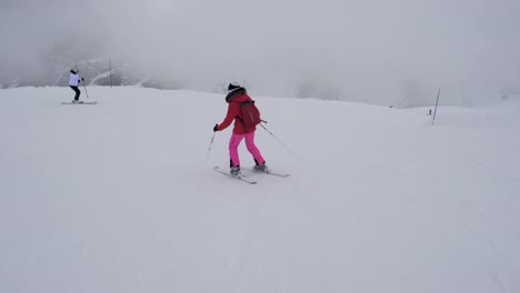 Two-Sporty-Female-Skiers-Skiing-On-The-Mountain-Downhill-In-Winter-In-Heavy-Fog