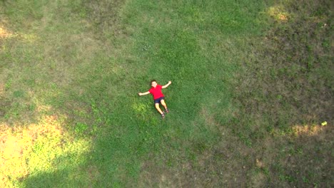 Little-boy-lying-down-in-the-middle-of-a-field.-Aerial-view