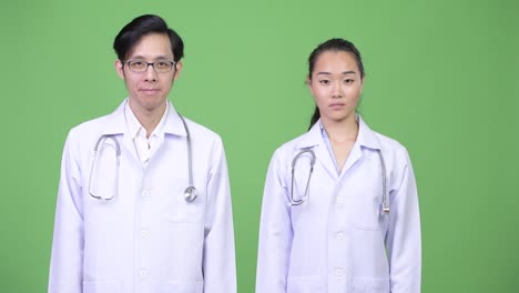 Médicos-de-la-joven-pareja-asiática-con-el-dedo-en-los-labios-juntos