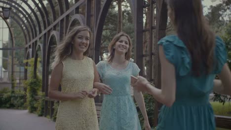 Two-cheerful-women-greeting-their-friend-in-park