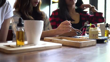 Friends-group-of-three-female-enjoy-eating-a-strawberry-cake-and-having-a-conversation-at-cafe-and-restaurant.-Underexposed-to-show-cinematic-look