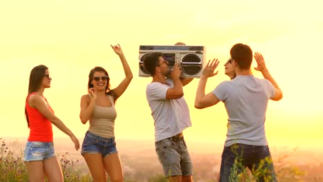 The-people-with-a-boom-box-dancing-on-the-sunrise-background.-slow-motion