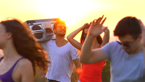 Las-cinco-personas-con-una-caja-de-auge-bailando-sobre-un-fondo-de-puesta-de-sol.-cámara-lenta