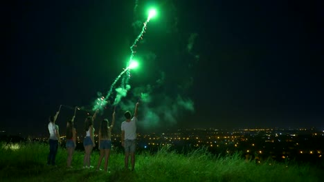 Die-fünf-Personen-halten-Sie-ein-Feuerwerk-auf-dem-Stadt-Lichter-Hintergrund-sticks.-Nachtzeit