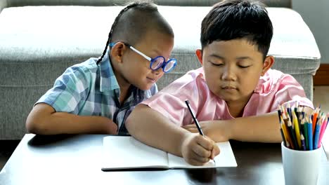 Boys-with-disability,-brain-disorders-And-Left-eye-is-not-visible-from-brain-surgery.--He-is-have-fun,-enjoy-write-in-book-with-friends-at-home.