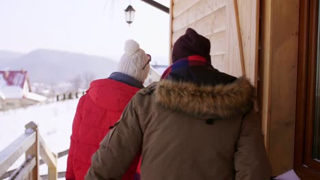 Rückansicht-des-Paares-verlassen-ein-Chalet-in-den-Bergen