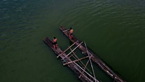 Aerial-view-of-Boys-jumping-into-water-in-lake-at-sunset,-joyful-in-countryside-life-concept