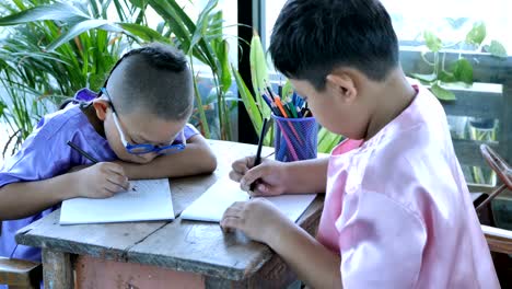 Feliz-niño-Asiático-con-escribir-en-el-cuaderno-y-lápices-de-dibujo-en-casa.-concepto-de-educación