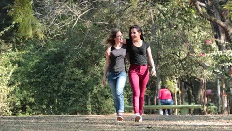 Two-girlfriends-together-walking-at-the-park-embracing-each-other