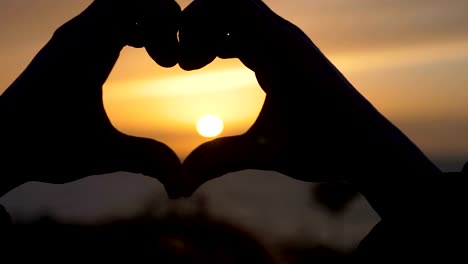 woman-hands-Making-heart-shape-at-the-sunset.-Love,Romance,nature