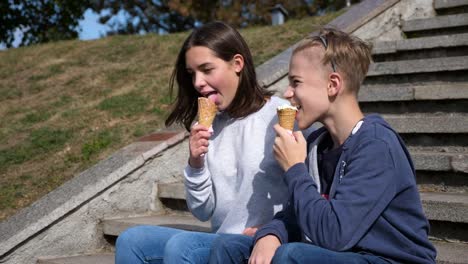 junges-attraktives-Paar-sitzt-auf-der-Treppe-lächelnd-und-Eis-essen