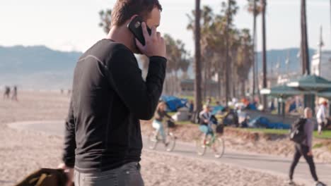 Tausendjährige-Mann-am-Telefon-auflegt-am-Strand