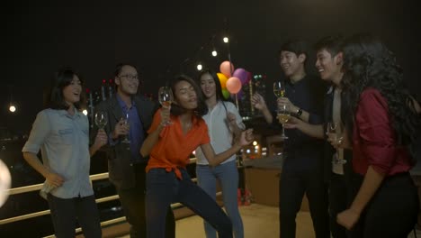 Group-of-young-friends-dancing-and-having-fun-celebrating-New-Year-and-Christmas-Festival-together-at-summer-rooftop-party.-Slow-motion.