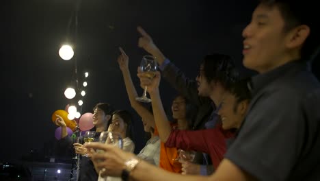 Grupo-de-jóvenes-amigos-bailando-y-divirtiéndose-celebrando-la-fiesta-de-Navidad-y-año-nuevo-juntos-en-la-fiesta-de-verano-en-la-azotea.-Cámara-lenta.