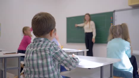 Educación-de-los-niños,-escolares-en-lección-escuchar-al-maestro-en-el-pizarrón-en-enfocada-en-aula-de-la-escuela