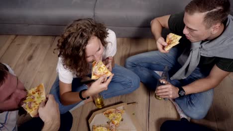 Freundschaft,-Essen,-inländische-Partyzeit---Pizza-bestellen-fröhlich-kaukasischen-Freunde,-Spaß,-auf-Boden-drinnen-sitzen-und-lachen,-Essen,-trinken.-Ansicht-von-oben