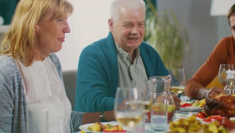 Familie-und-Freunden-am-Esstisch-zu-sammeln.-Älteres-paar-sprechen,-scherzen-und-Essen.