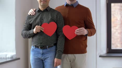 männliche-Homosexuelle-paar-mit-roten-Herzformen-zu-Hause