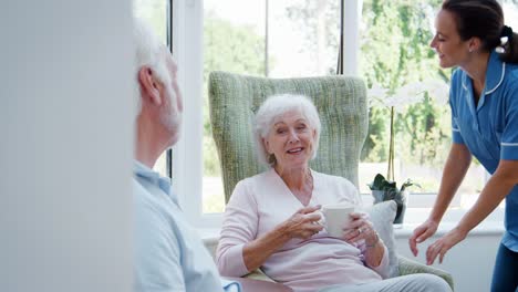 Älteres-Paar-sitzt-im-Stuhl-und-im-Gespräch-mit-der-Krankenschwester-im-Altenheim