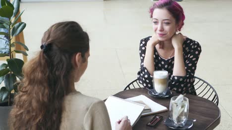 Frauen-skizzieren-und-sprechen-im-café