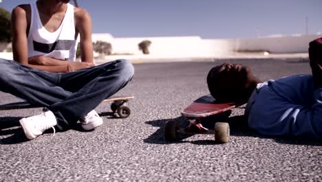 Teenager-longboarder-Sitz--und-liegen-auf-ihren-Brettern-zu