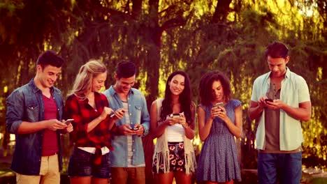 Happy-friends-in-the-park-using-their-phones