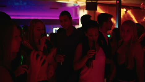 Friends-toasting-and-holding-beer-high-at-a-party-on-dance-floor