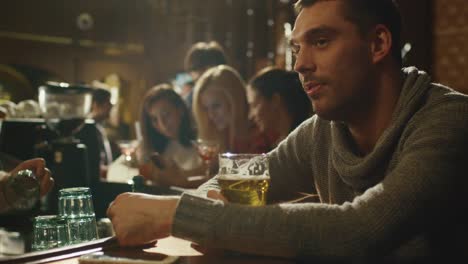 Attractive-man-is-drinking-lager-beer-in-a-crowded-pub.