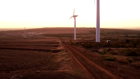 Friends-enjoying-a-road-trip-through-wind-farm-at-sunset