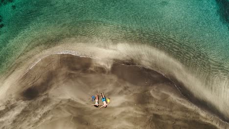 Aerial-view-of-young-couple-relaxing-on-tropical-beach-on-vacation