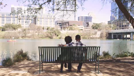 African-American-couple-sitting-together-on-a-bench-on-the-city-waterfront