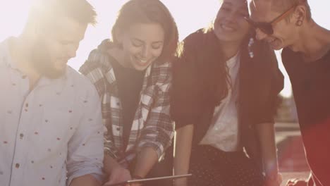 Group-of-Teenagers-Using-Tablet-Computer-for-Entertainment-Outdoors-in-Urban-Environment