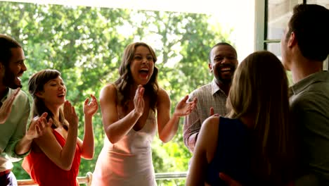 Happy-couple-embracing-while-friends-applauding-during-party