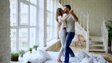 Young-beautiful-and-loving-couple-dancing-and-kissing-on-bed-in-the-morning-at-home