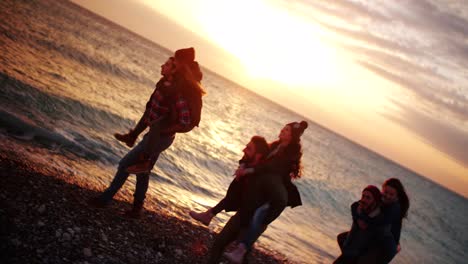 Freunde-geben-Huckepack-Fahrten-am-Strand-bei-Sonnenuntergang