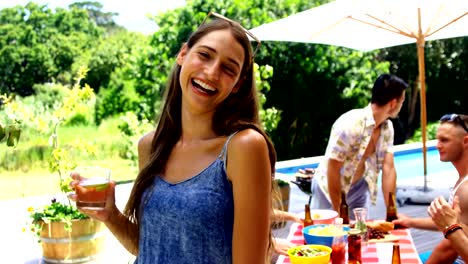 Happy-woman-looking-at-friends-behind-while-having-cocktail-drink