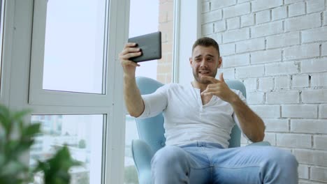 Young-attractive-couple-having-online-video-chat-using-tablet-computer-sitting-at-balcony-in-modern-loft-apartment