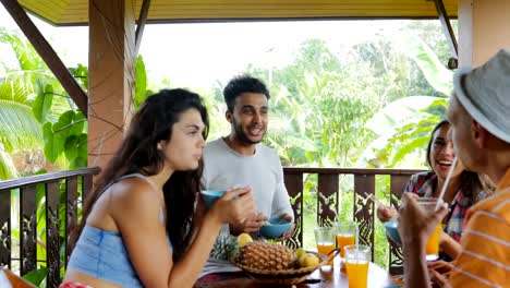 Menschen-essen-Nudeln-sprechen,-Freundesgruppe-sitzen-am-Tisch-auf-der-Terrasse-mit-Blick-auf-den-tropischen-Wald