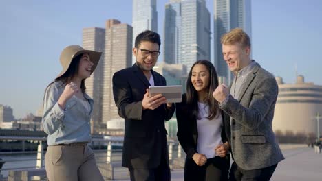 Young-Gender-Mixed-Diverse-Group-of-Friends-Using-Digital-Tablet.-Talking,-Discussing-und-Cheering-in-the-City.