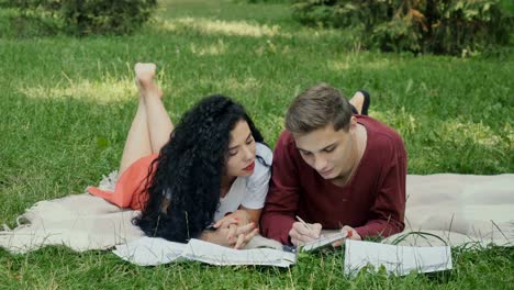 Students-prepares-to-exams-in-park,-guy-writes-some-information-in-notebook