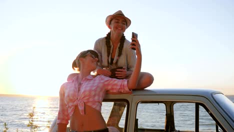 photo-at-mobile-of-Beautiful-Friends-near-automobile-on-shore-river,-Lovely-girls-Photographed-near-vehicle