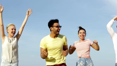 Gente-feliz-saltando-por-encima-de-cielo-azul,-grupo-de-jóvenes-amigos-alegres-al-aire-libre