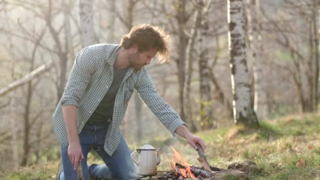 Man-lighting-fire-place-putting-wood-logs.real-friends-people-outdoor-camping-tent-vacation-in-autumn-trip.Fall-sunny-day-in-nature,-togetherness-and-friendship.-4k-video