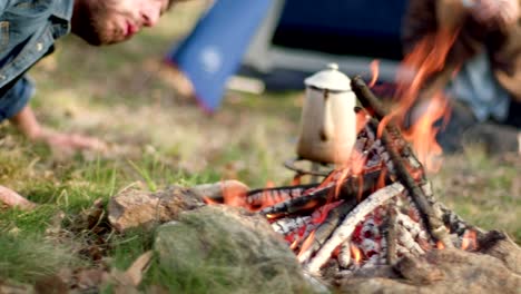 Man-lighting-fire-place-blowing.real-friends-people-outdoor-camping-tent-vacation-in-autumn-trip.Fall-sunny-day-in-nature,-togetherness-and-friendship.-4k-video