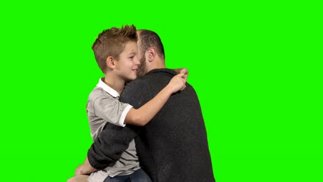 Little-boy-whispers-secret-on-ear-of-his-elder-brother-at-green-background