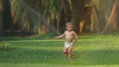 Schöne-Szene-von-Säugling-Kleinkind-Baby-läuft-im-grünen-Bereich-mit-Wasser-besprengt-während-des-Sonnenuntergangs-goldene-Stunde-Mal-in-4-k-Clip-Auflösung.-Zeitlupen-60fps-des-Säuglings-laufen-schönen-ehrlichen-Moment-in-4k