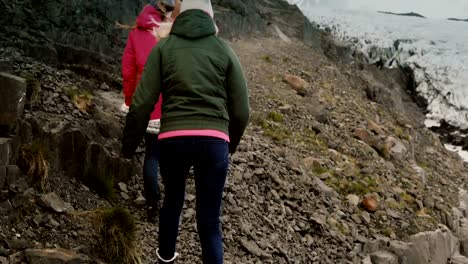 Group-of-young-people-walking-through-the-rocks,-hiking-in-mountains-together-near-the-Vatnajokull-ice-lagoon-in-iceland