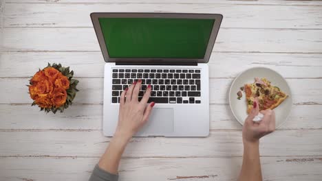 Mädchen-auf-Laptop-Pizza-essen.-Ansicht-von-oben.-Hände,-Nahaufnahme